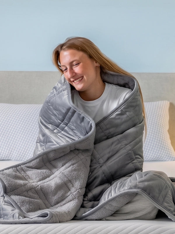 Vrouw omhelst zichzelf gewikkeld in een grijze verzwaringsdeken.