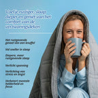 Vrouw ontspant met een warme drank onder de Ella verzwaringsdeken met kap.