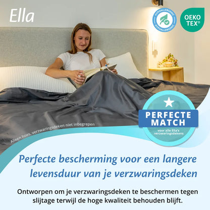 Vrouw leest in bed onder een antracietgrijze Ella hoes voor verzwaringsdeken, met OEKO TEX en hypoallergeen icoon.