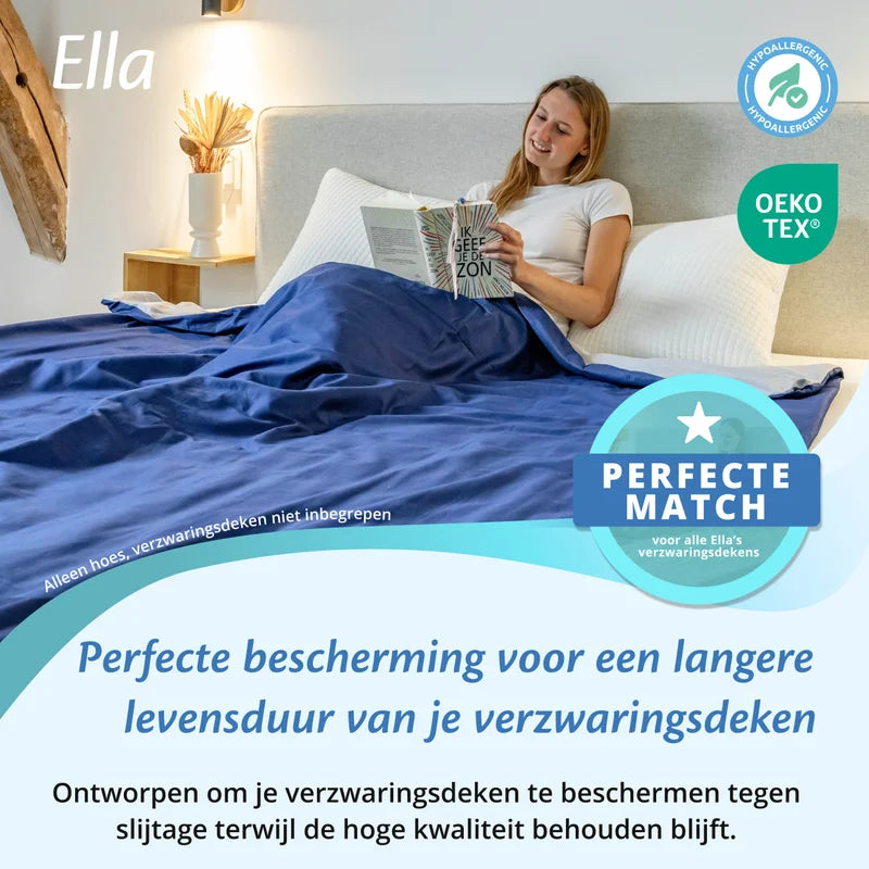 Vrouw leest in bed onder een grijs en blauwe katoenen Ella hoes voor verzwaringsdeken, met OEKO TEX en hypoallergeen icoon.